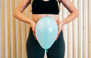 A photo of a woman holding a balloon in front of her pelvis and abdomen.